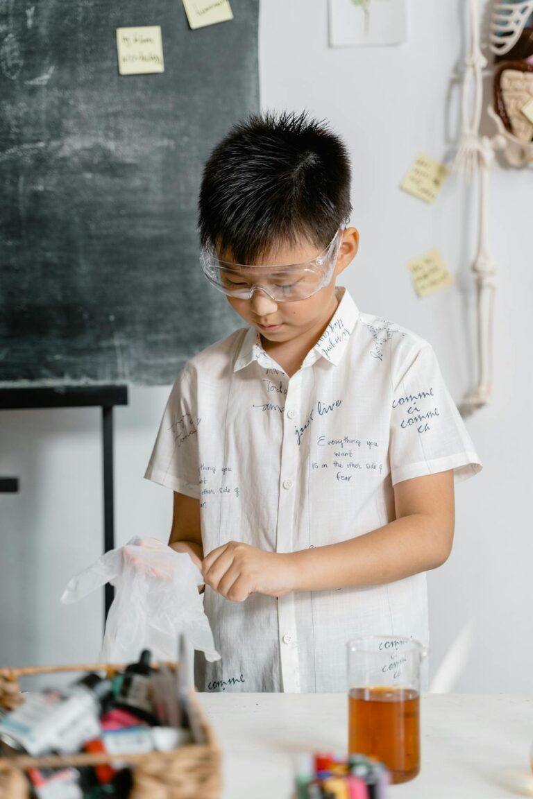 A child wearing safety glasses and gloves conducts a science experiment indoors.