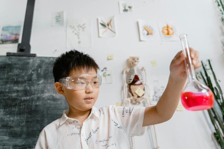 A young boy conducts a chemistry experiment with a beaker in a classroom setting.