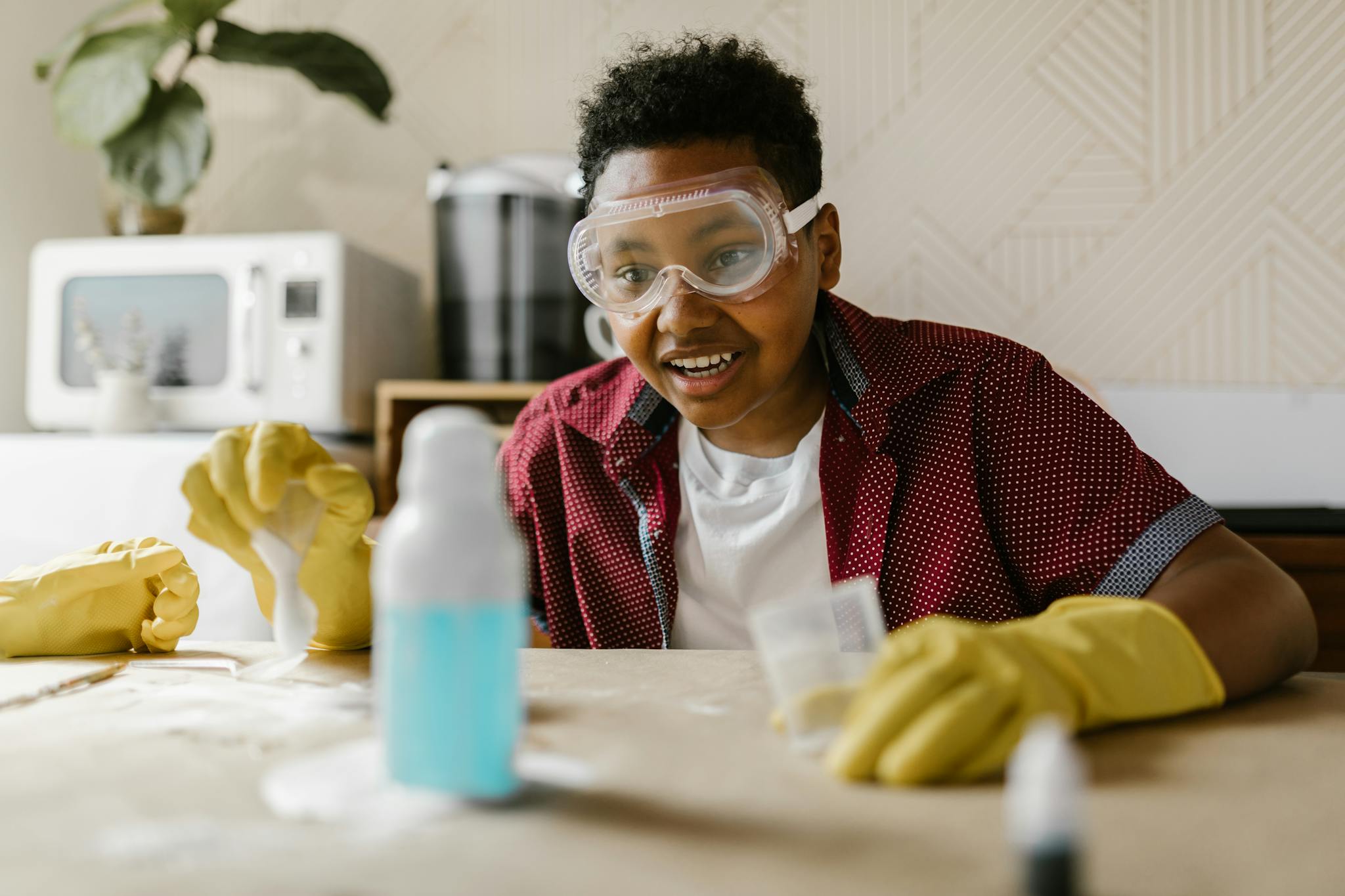 A young boy in goggles and gloves explores science in a fun home experiment setting.